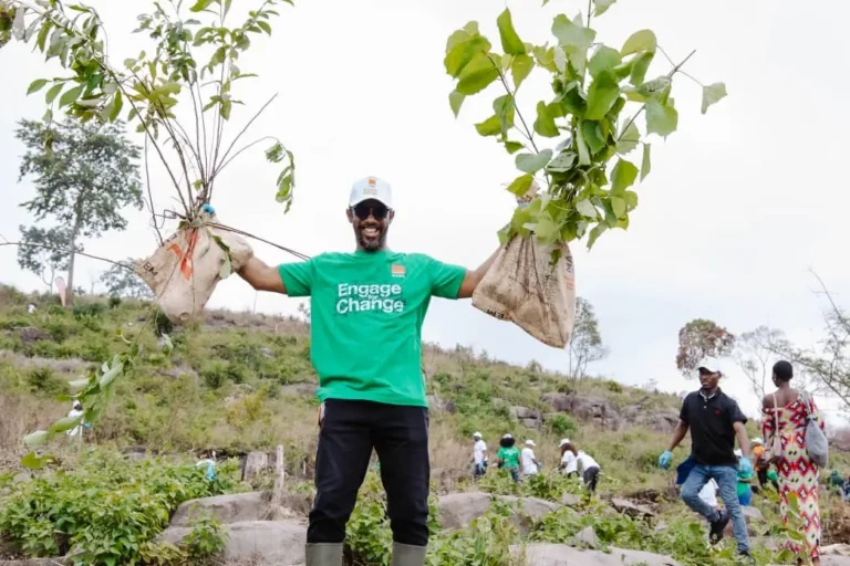 Orange and Tacugama team members working together to plant young tree saplings in a degraded area of the Western Area Peninsula National Park on World Environment Day